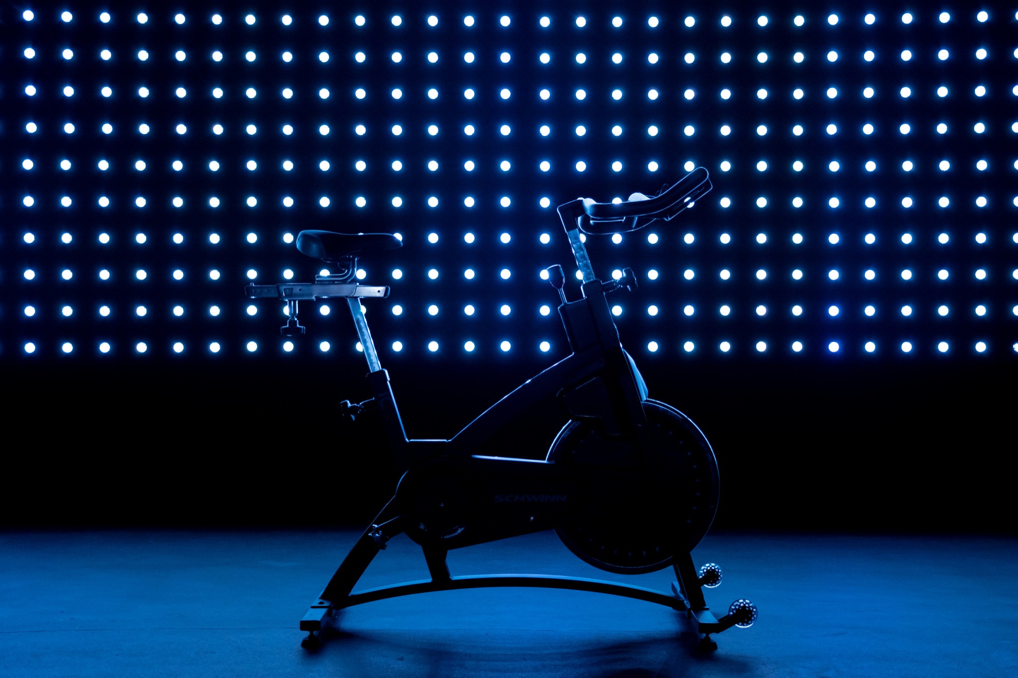A spin bike silhouetted against a wall of blue LED dots