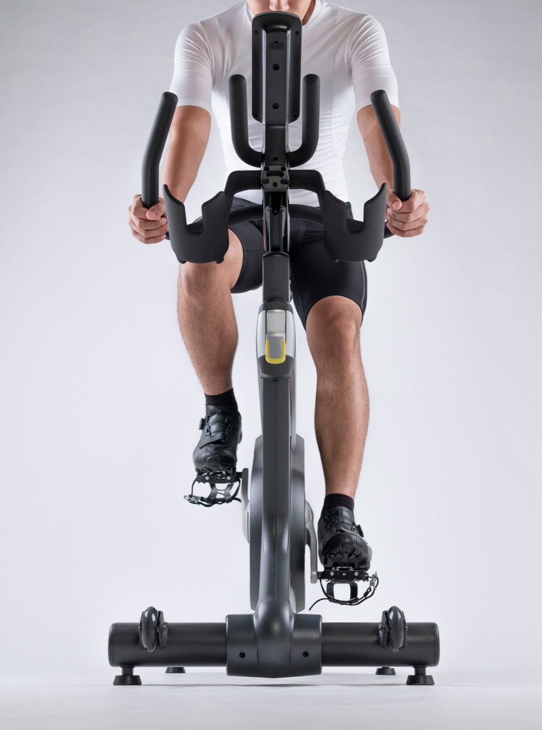Front-on view of a rider clipped into a studio bike, white backdrop